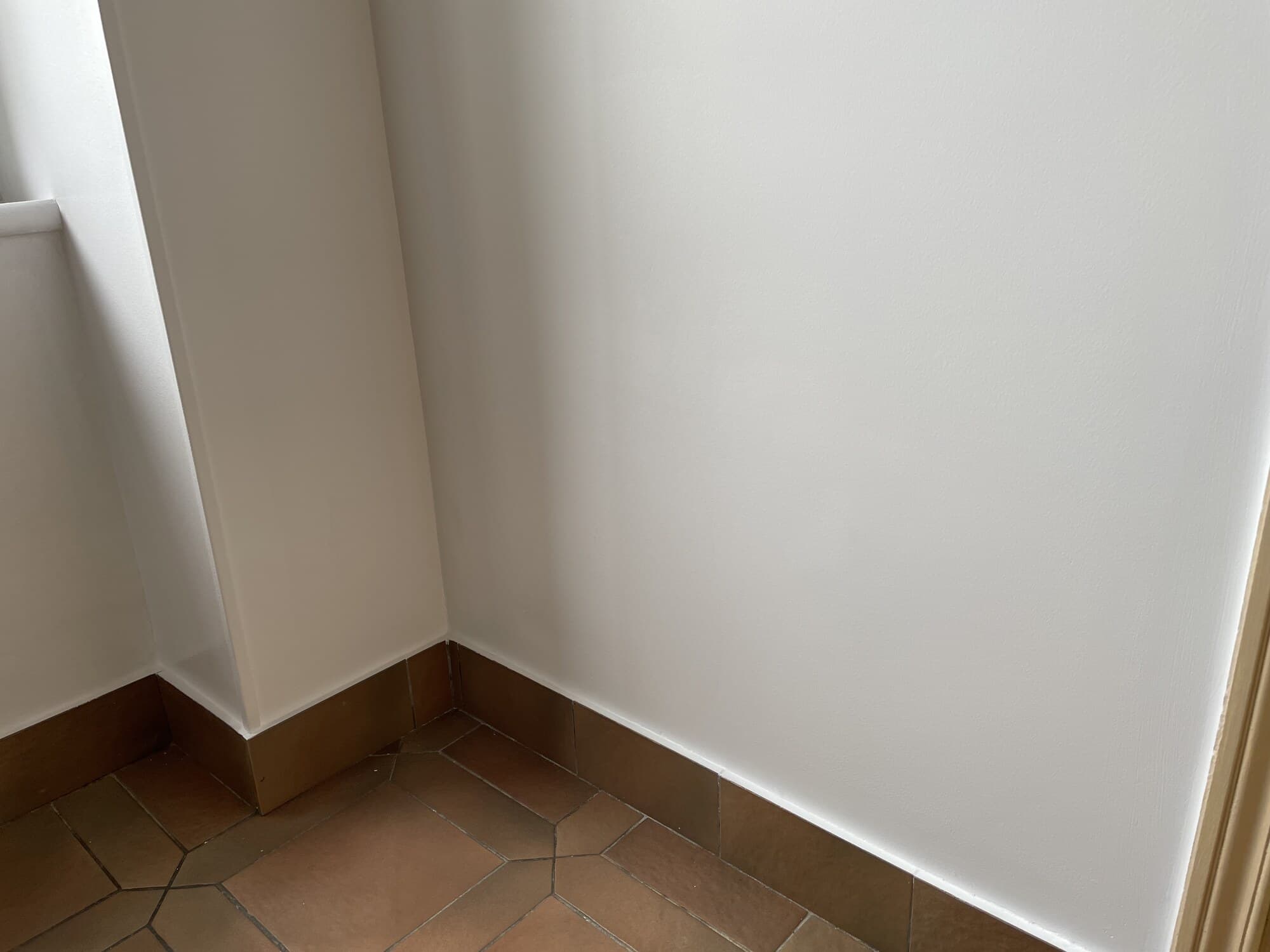 Angle de mur blanc avec tomettes et plinthes bois