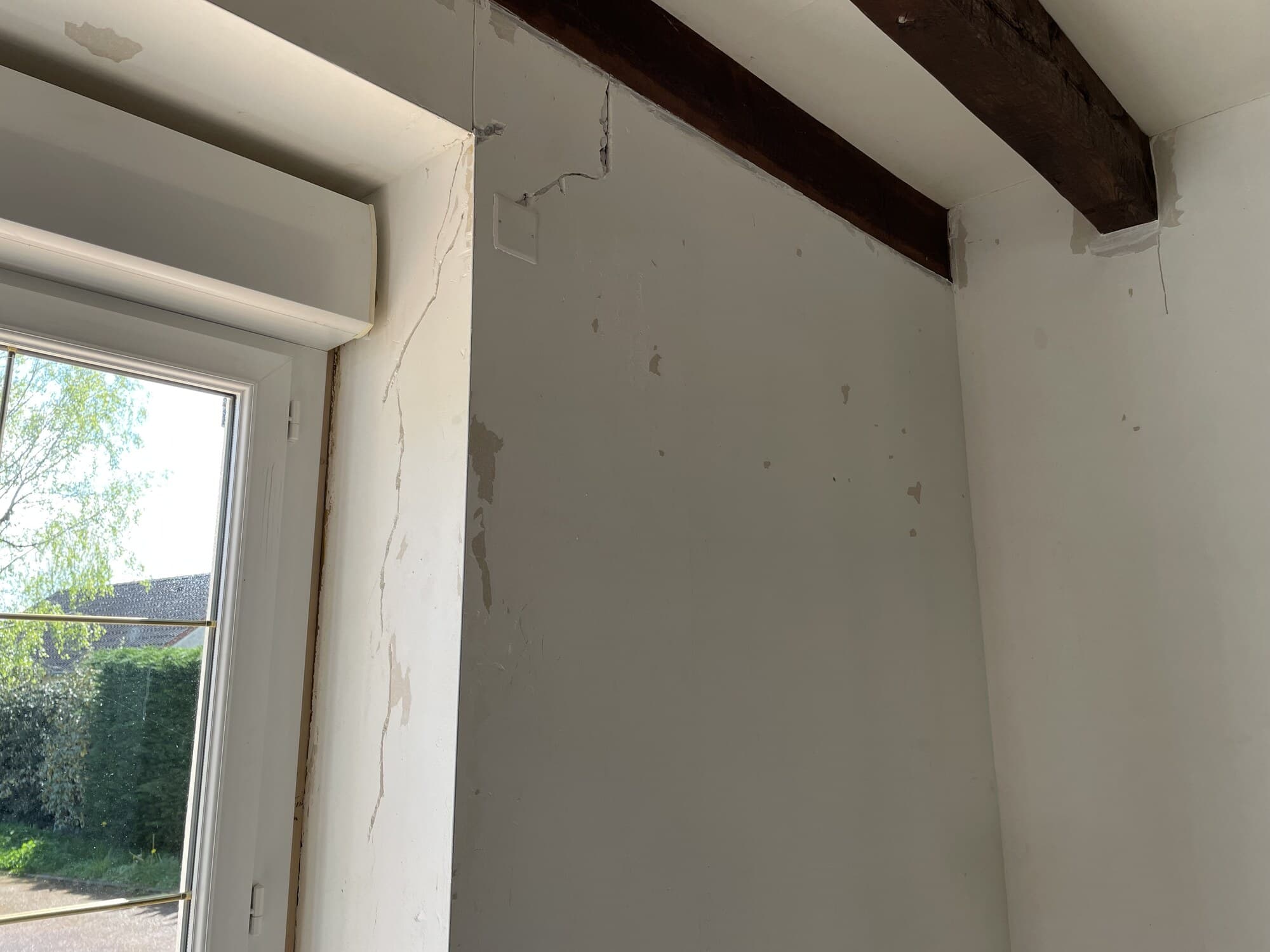 Détail mur intérieur en préparation avec poutre apparente et fenêtre