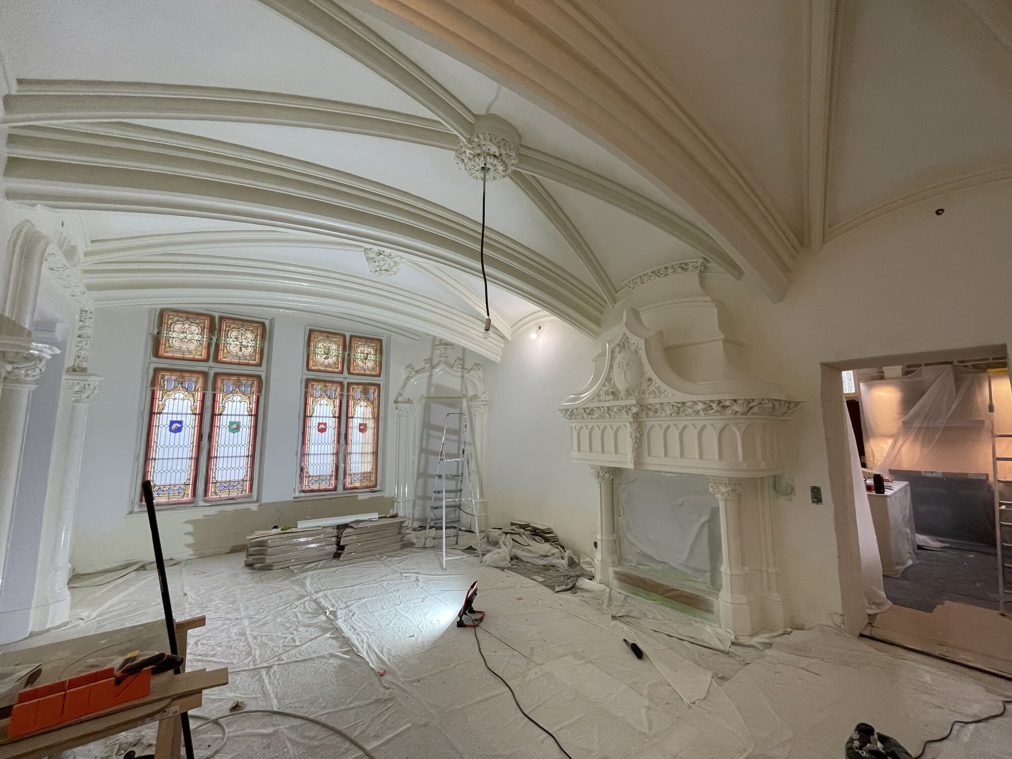 Vue large d'une salle de château avec voûtes et vitraux