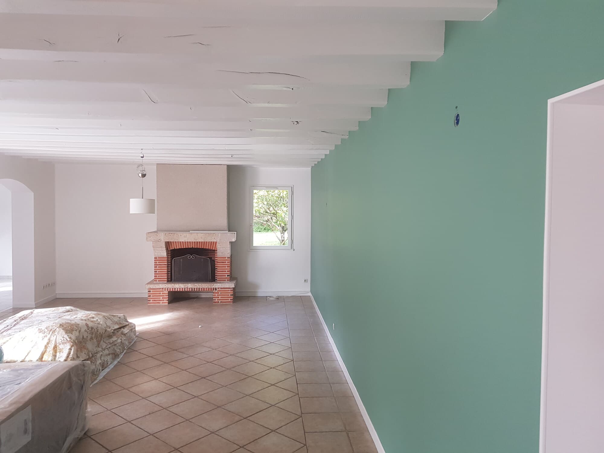 Salon avec cheminée brique et mur vert pâle après peinture