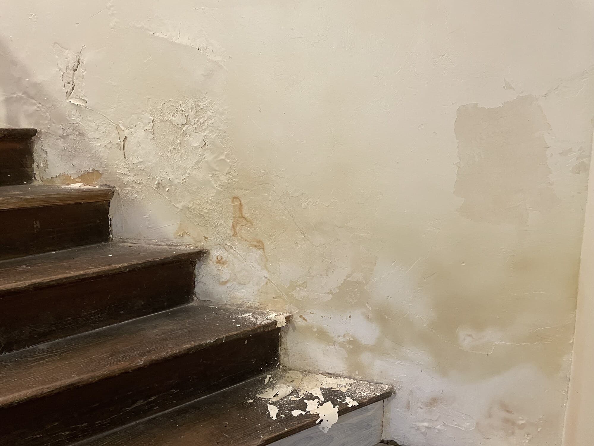 Cage d'escalier avec mur abîmé par l'humidité avant rénovation