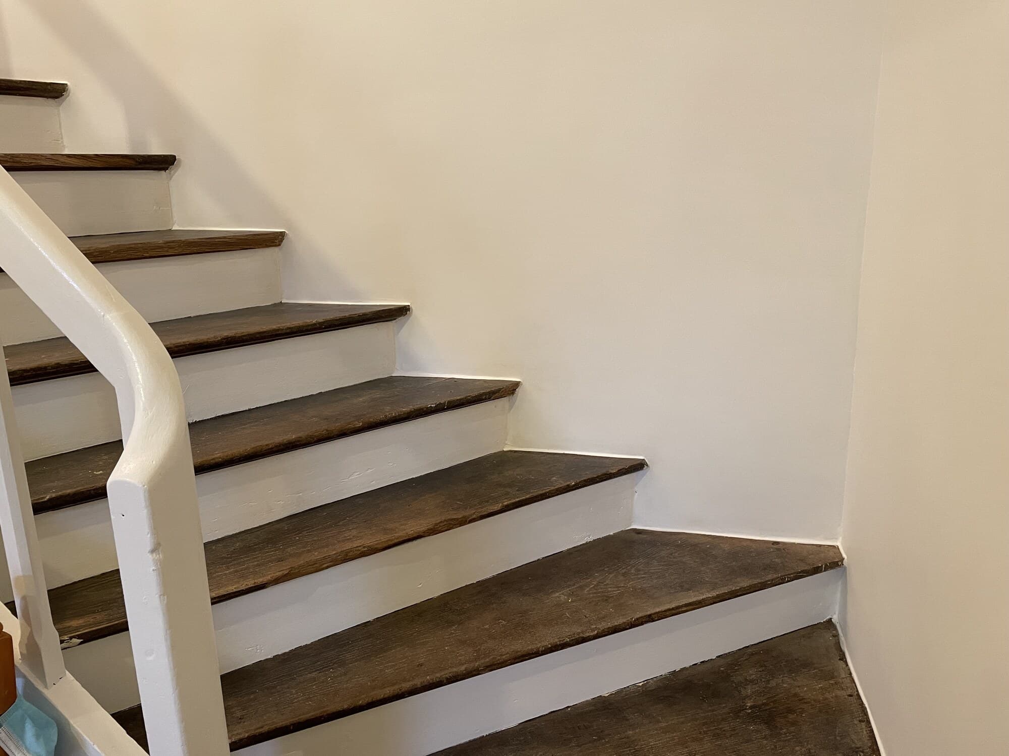 Cage d'escalier rénovée avec mur blanc et contremarches peintes