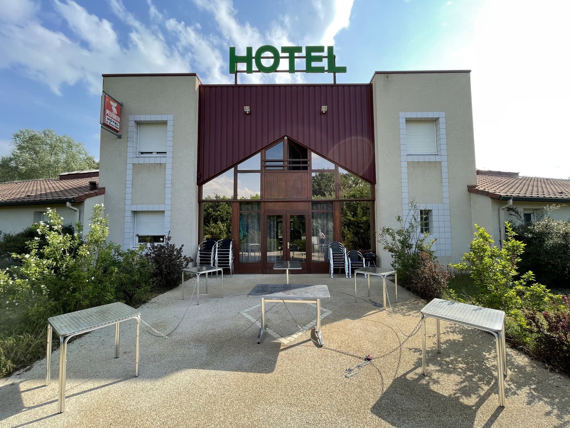 Façade d'hôtel avec entrée vitrée et mobilier de terrasse