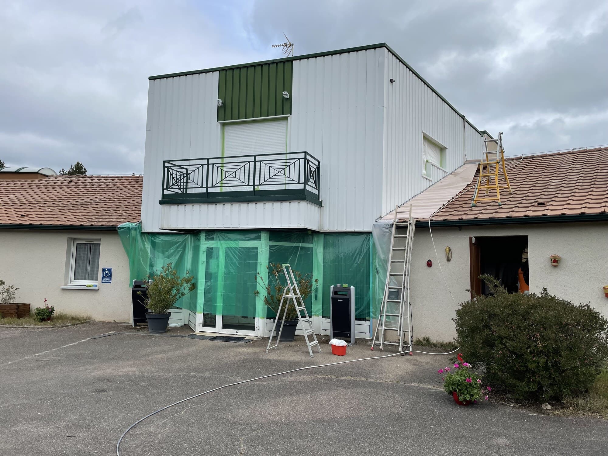 Façade d'hôtel en chantier avec bâche de protection verte