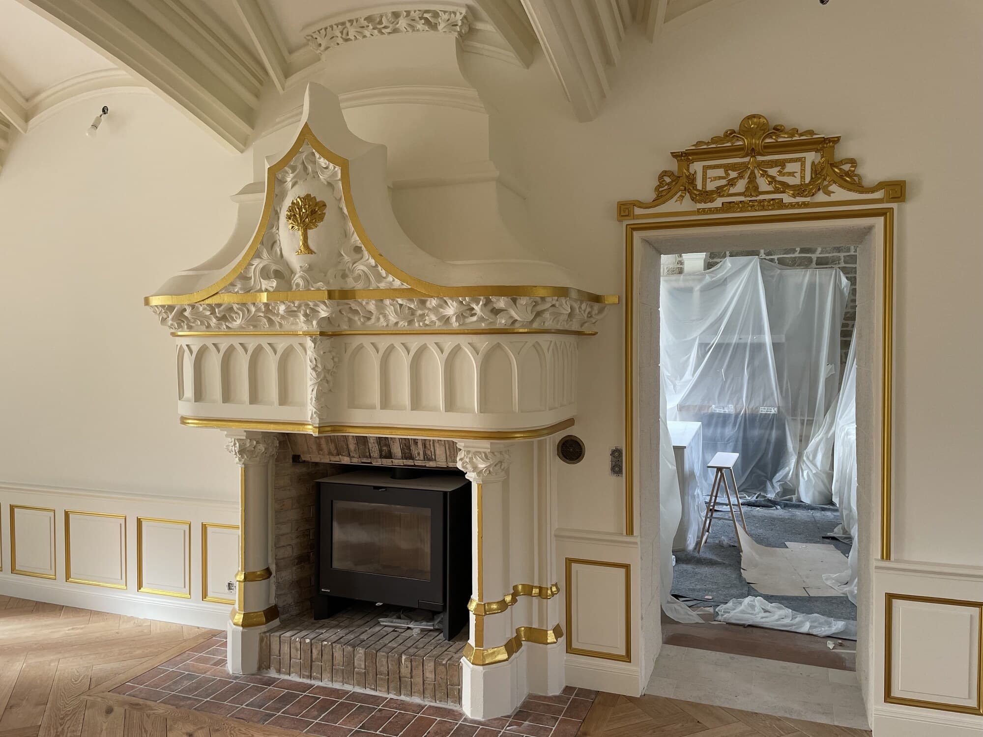 Cheminée sculptée or et blanc avec poêle à bois moderne dans château