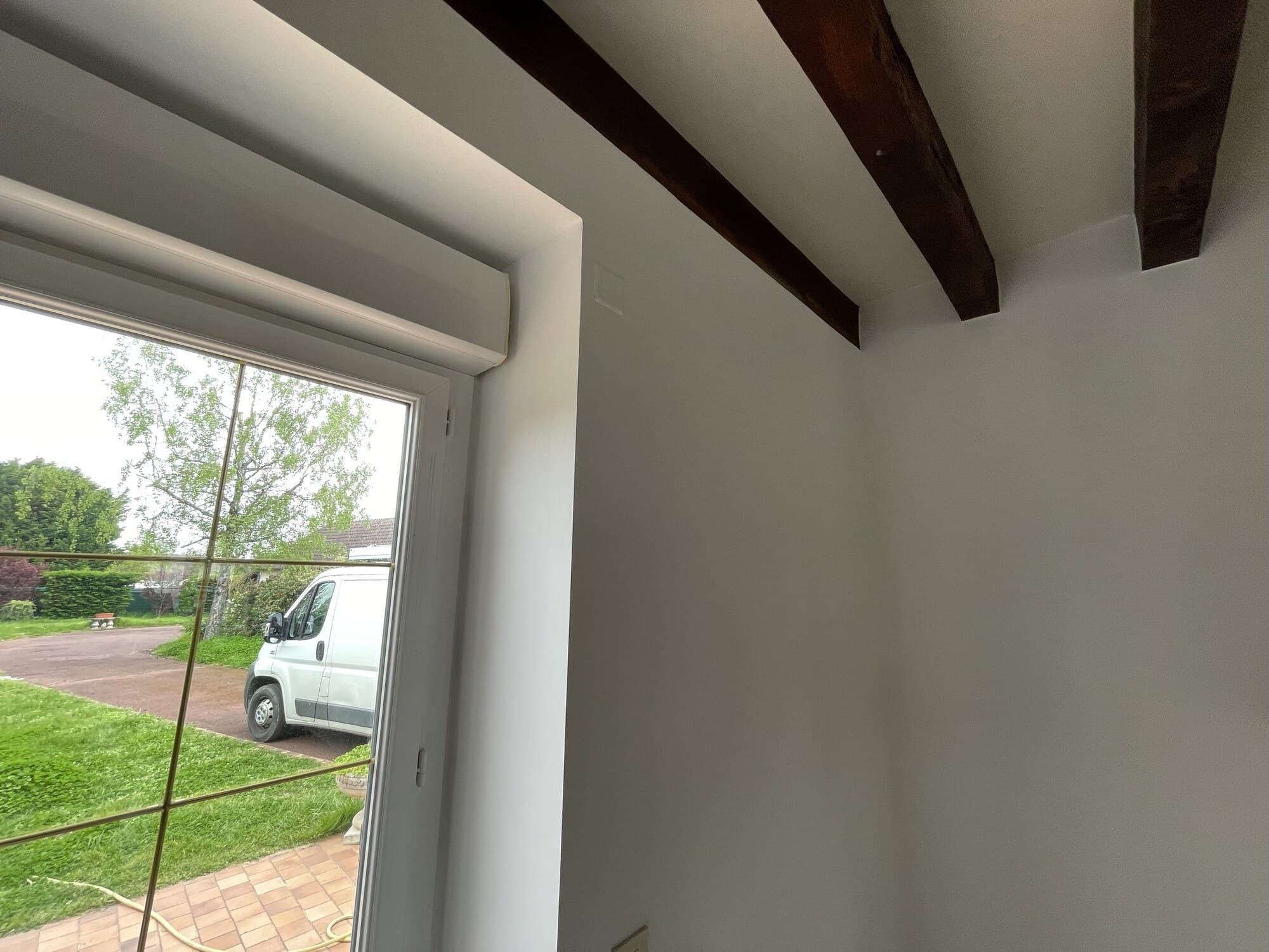 Vue d'une fenêtre avec poutres apparentes au plafond