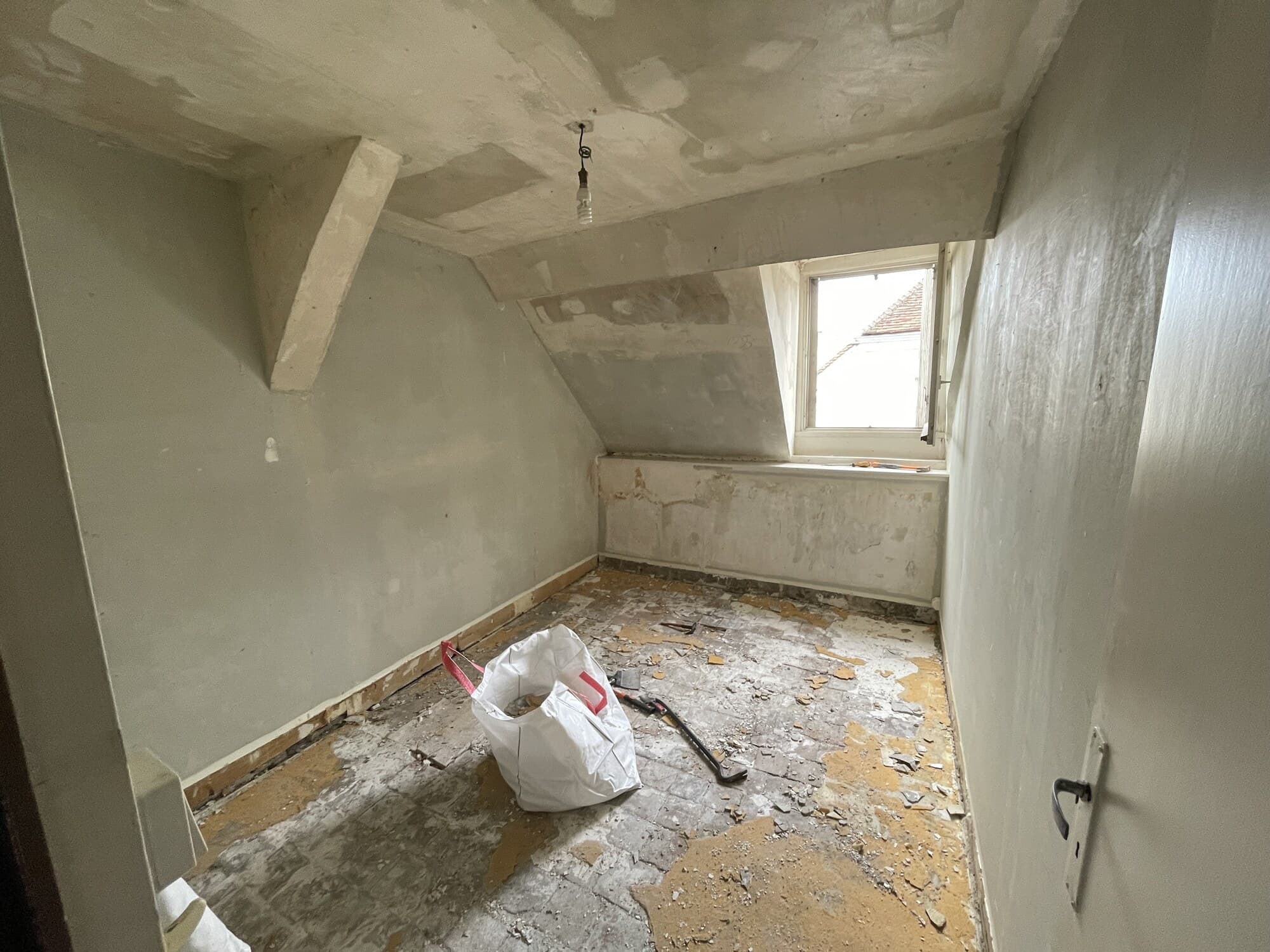 Pièce dans les combles en préparation avec velux et débris