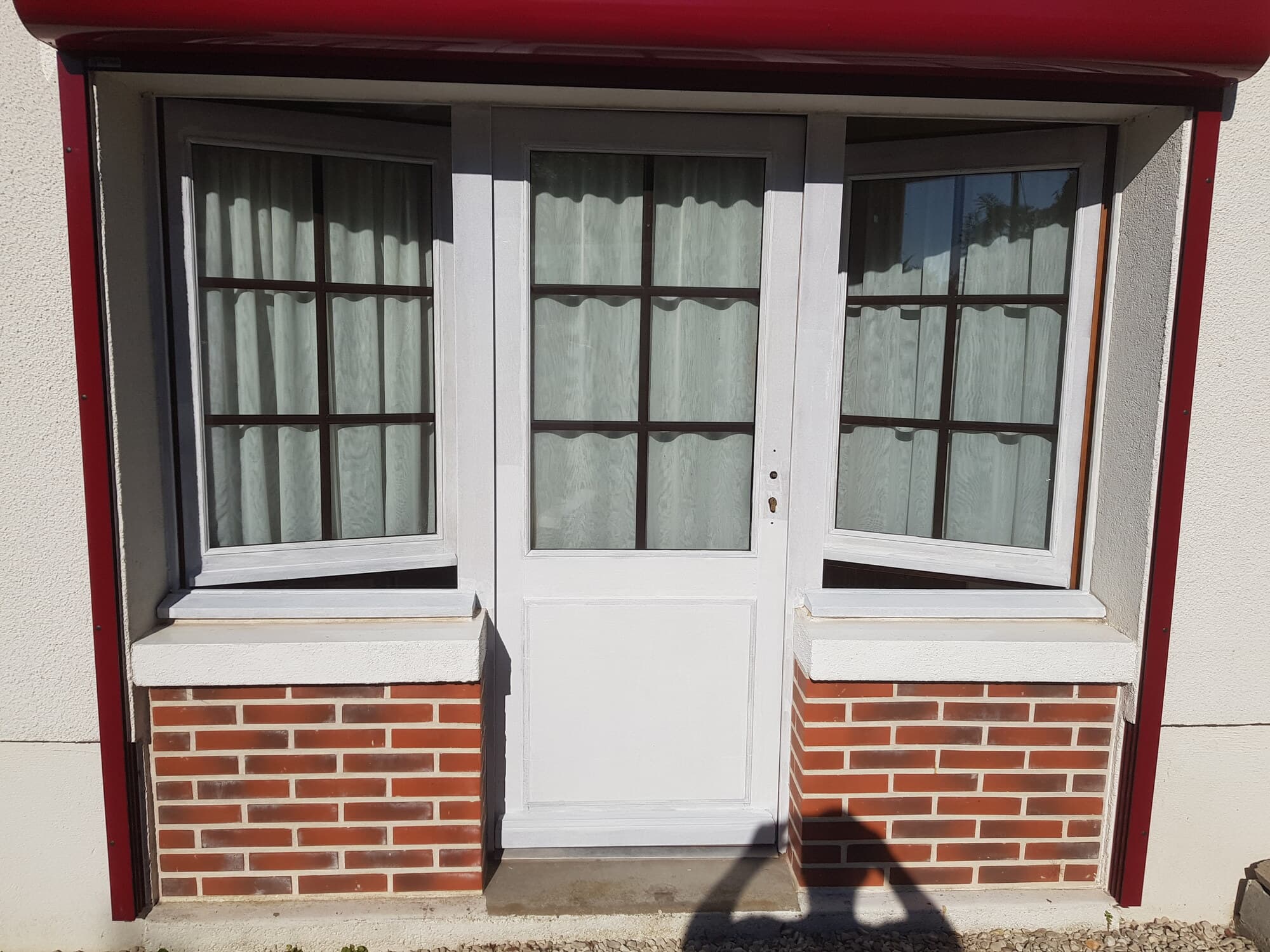 Porte d'entrée peinte en blanc sur soubassement de briques