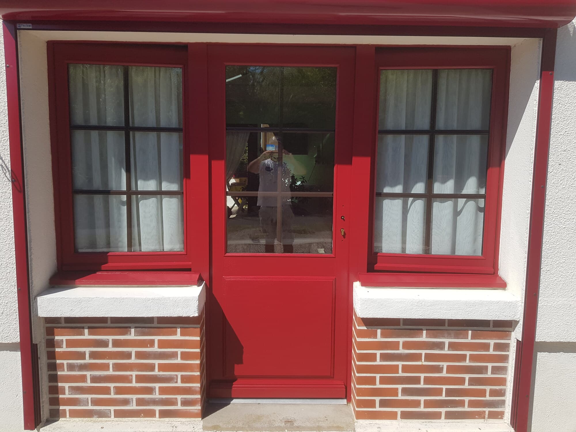 Porte d'entrée peinte en rouge sur soubassement de briques