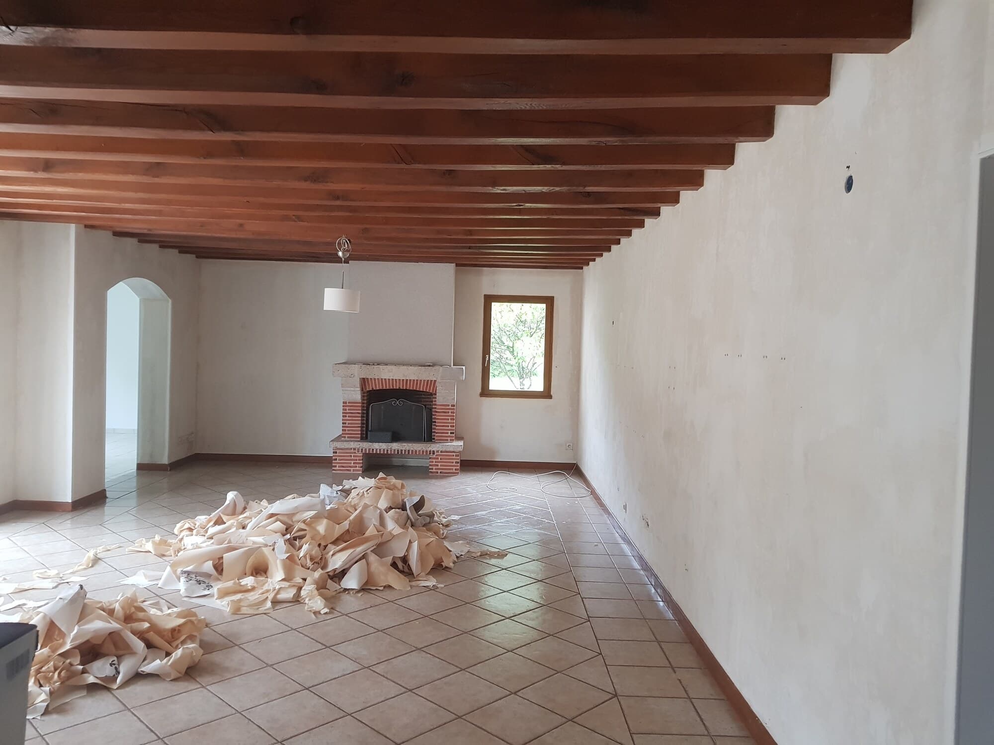 Salon avec cheminée brique et plafond poutres apparentes en chantier