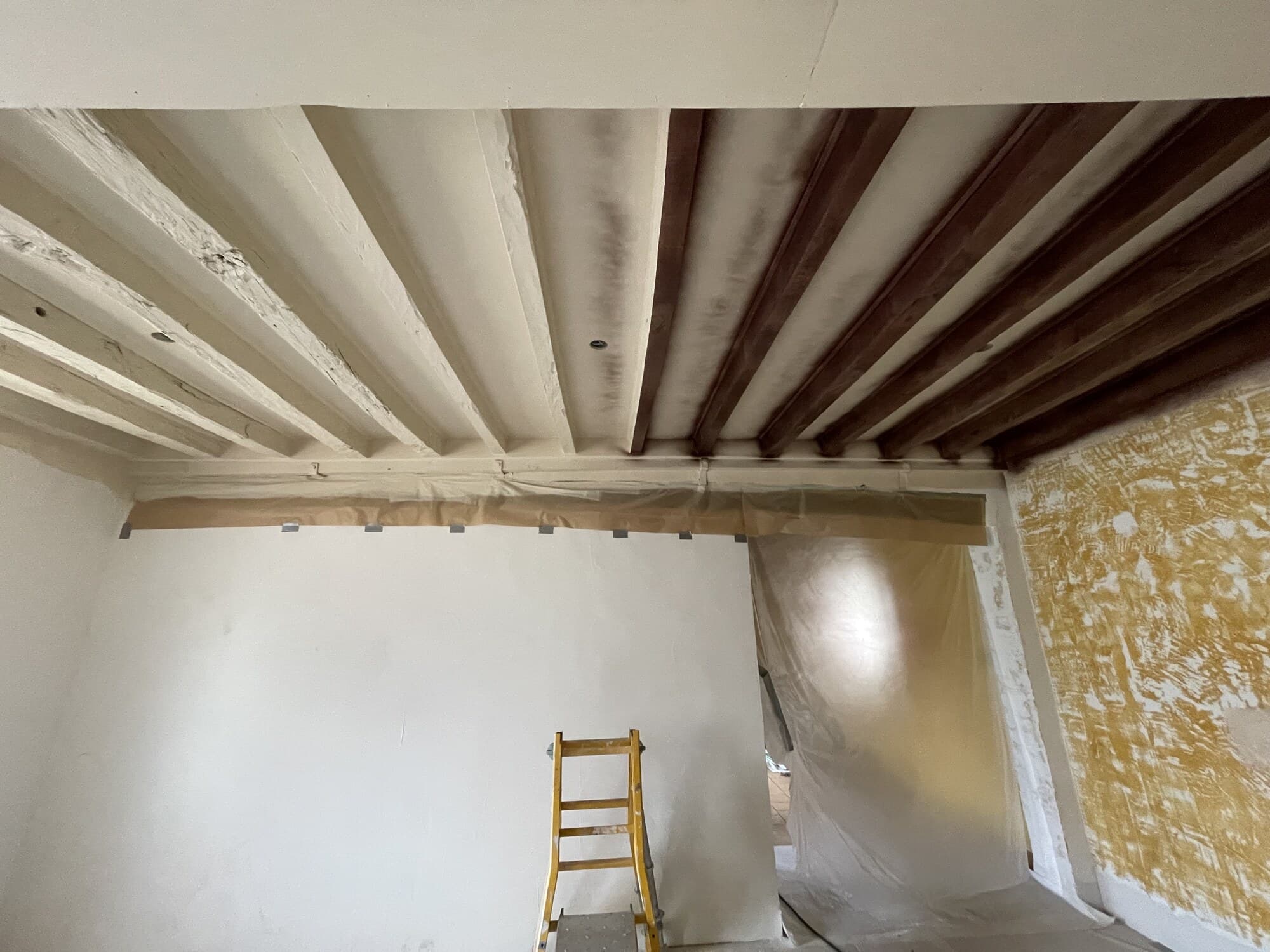 Plafond avec poutres apparentes en cours de mise en peinture
