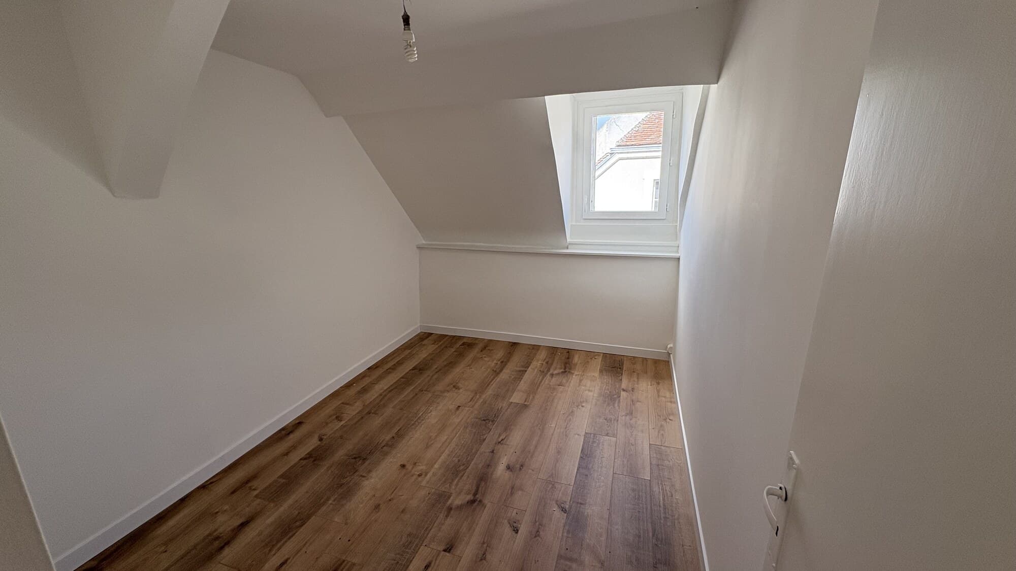 Chambre dans les combles rénovée avec parquet bois et velux