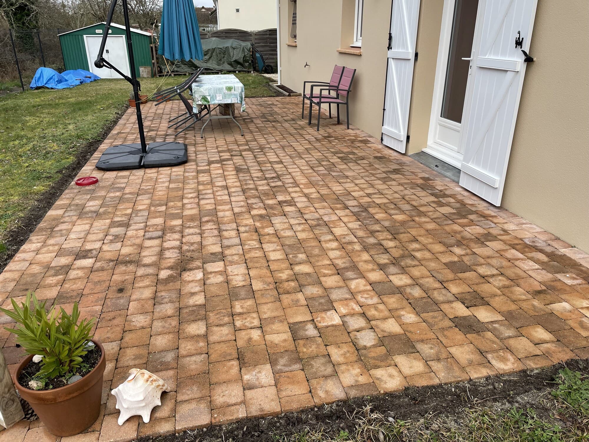 Terrasse en pavés autobloquants avec parasol et chaises de jardin