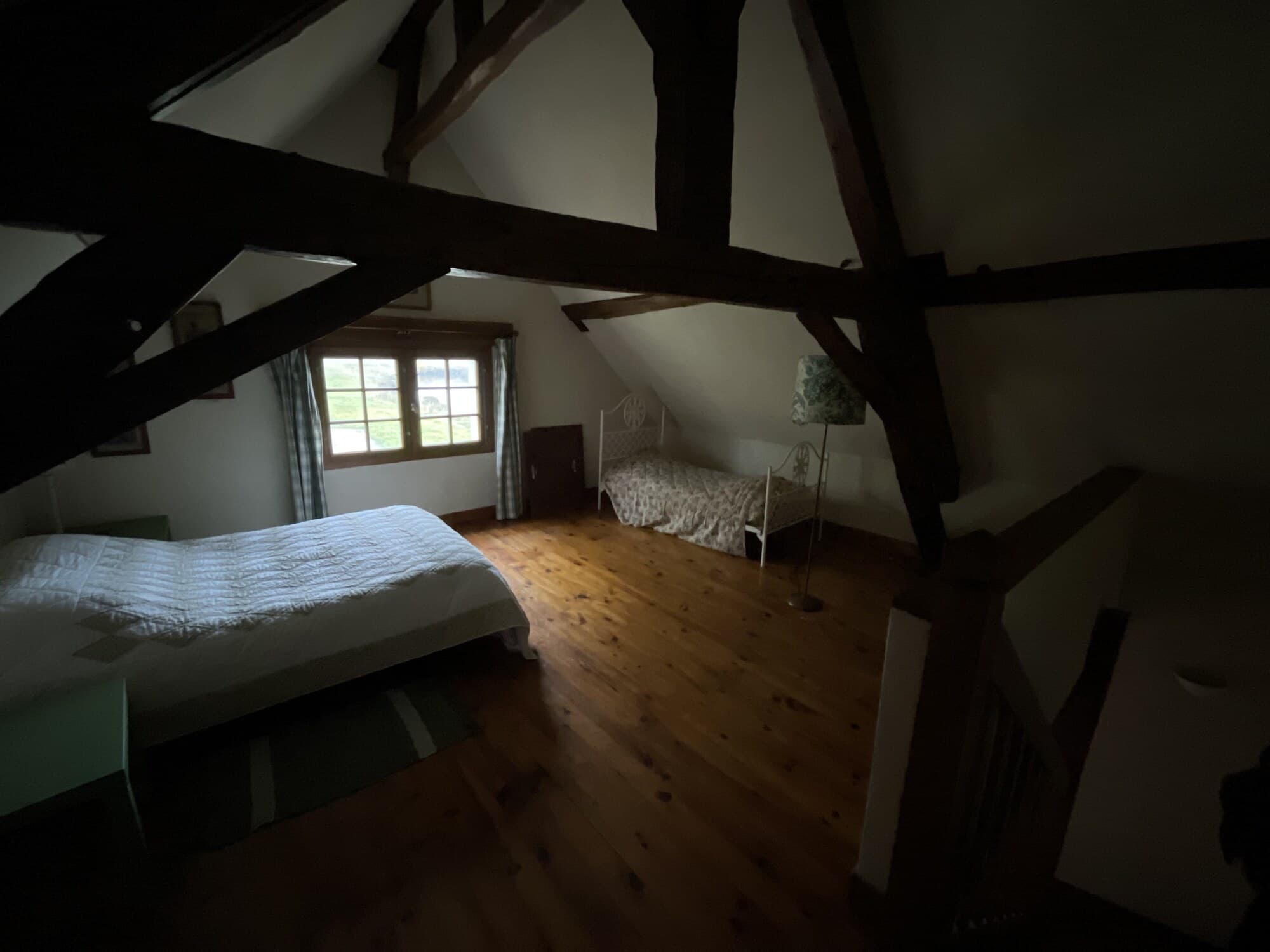 Chambre dans les combles avec poutres apparentes et deux lits
