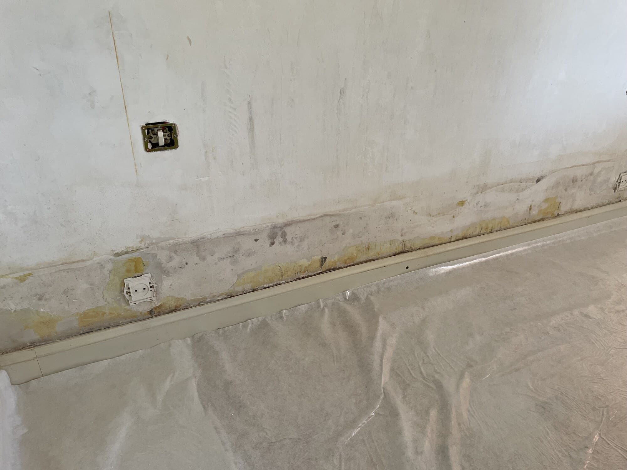 Mur intérieur avec traces d'humidité et plinthe à remplacer