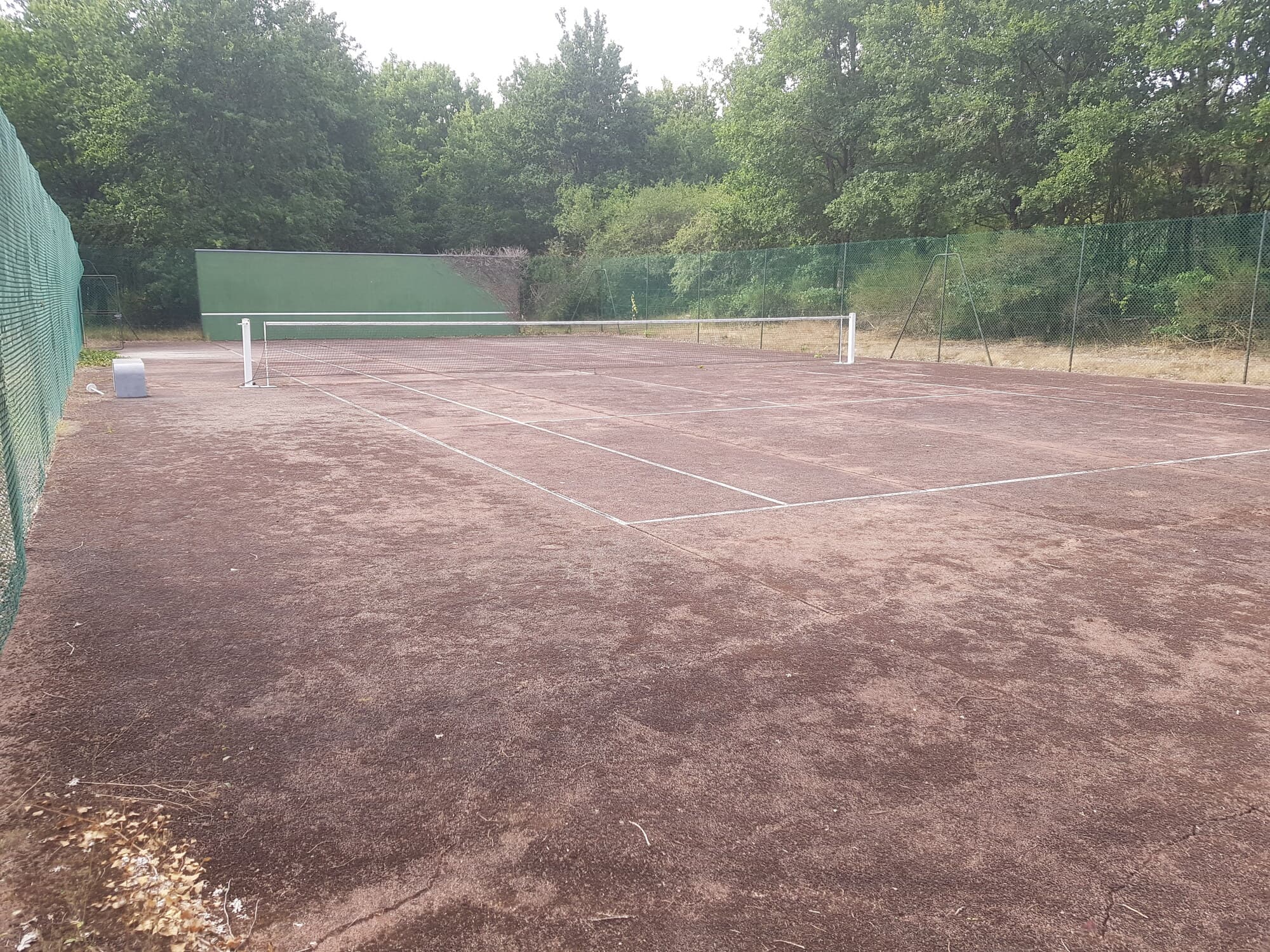 Vue large d'un terrain de tennis rouge usé
